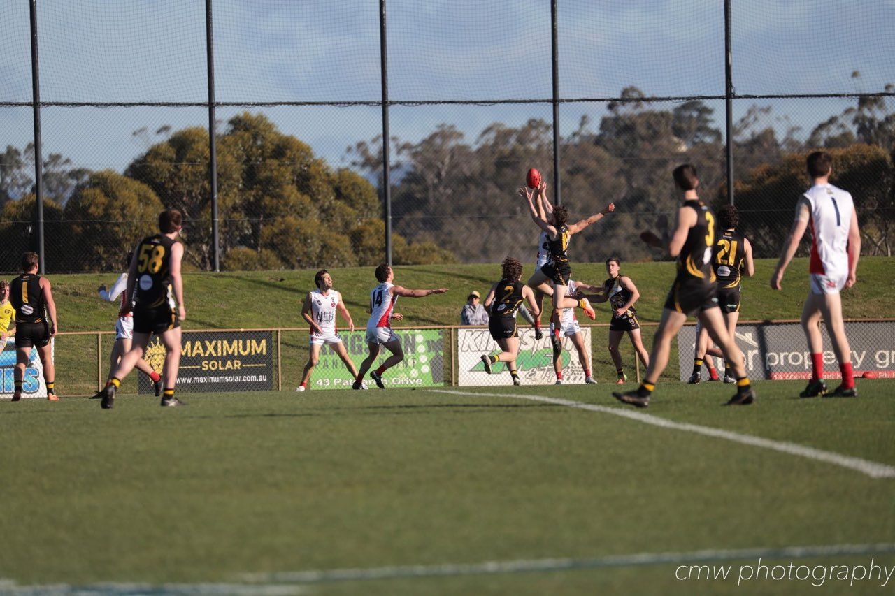 Footballers contesting a mark in front of Maximum Solar boundary signage